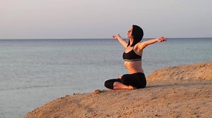 Beautiful Woman doing yoga on Marine Beach. One Adult Girl at Bright Scenic Sea. Modern Romance of Ocean Bathing and Amazing Summer Sky at Sundown.