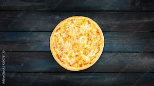 Rotating pizza margarita on a dark wooden background. Top view center orientation