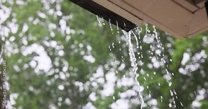 During heavy rain, water cascades from overflowing gutters.