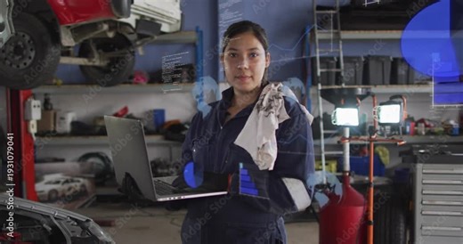 Female auto technician holding laptop in garage, glancing and activating HUD charts, diagnosing car