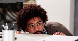 clip-1097931471-scared-man-hiding-behind-office-desk-room