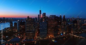 Approaching high-rise buildings with switched on lights in the windows in Manhattan, New York, the USA. Beautiful pink sky at backdrop.