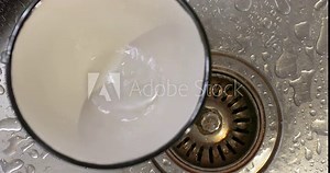 Dripping kitchen faucet over sink drops falling in a used tea cup
