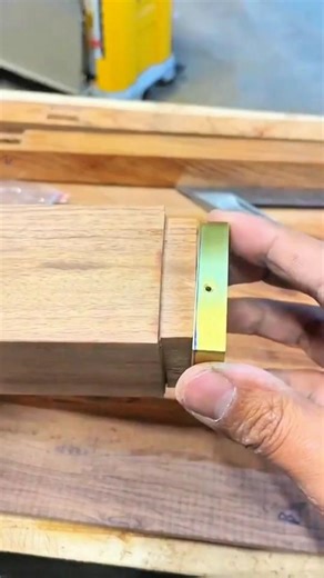 Brass guide sets chisel angle—hand steadies hardwood as miter edge takes crisp, golden form.