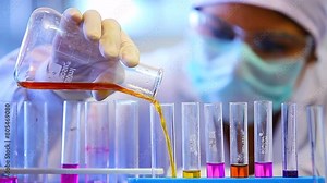 scientist mixing colourful chemicals. chemist experimenting. science experiment in a beaker flask titration with colorful chemicals liquid in laboratory with medical lab equipment. Scientist