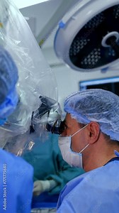 Upper part of a male doctor looking at binoculars of microscope. Surgery on a brain in progress. Vertical video.