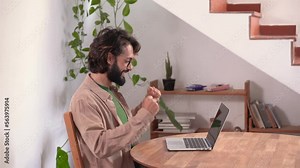 Happy entrepreneur working from home with laptop stretches and puts his arms behind his head happy for the success at work. Freelance guy starting small business. High quality 4K video footage