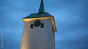 Clock on church tower shows twenty minutes to six while the camera slowly spins around the tower.