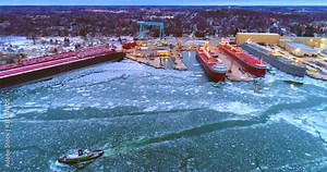 Giant Great Lakes freighter ships being built, refurbished, repaired, in icy cold waters, aerial view.