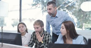Young bussiness colleagues working in an office. Senior supervisor standing and giving advice. Successful team solving a problem.