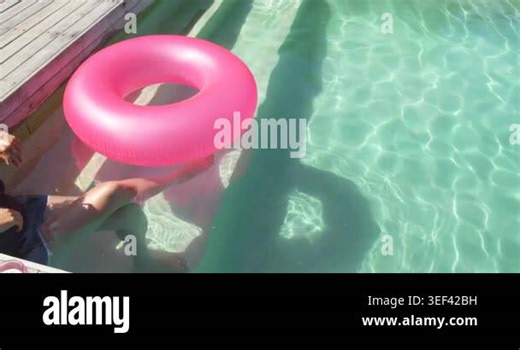 Holding pink ring on pool-deck African American woman steadying lowering to float, copy space. Inflatable, outdoor, sunny, water, reflections, shadows, overhead Stock Video Footage - Alamy