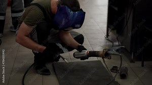 Auto repair tech welds car exhaust, sparks fly from catalyst welding. Flex pipe repair in garage, mechanic fixes vehicle muffler. Automotive workshop service, expertise in action, maintenance work.