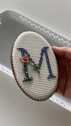 La M di Manu. Biscotto con una M "ricamata" con ghiaccia reale. Ho glassato con ghiaccia reale il biscotto di pasta frolla al cacao. Ho realizzato la griglietta di pizzo edibile con glassa @sugarveil e il loro tappetino Needlepoint Mat e l'ho incollata al biscotto, glassata con ghiaccia reale, con un pennello inumidito con acqua. Clicca su Abbonamenti qui su Facebook e impariamo insieme a fare questo biscotto e altri due ancora (questo tutorial specifico è in inglese, con i sottotitoli, ma se c’