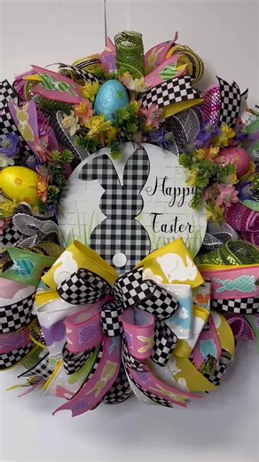 This beautiful Easter Egg Wreath is made with black and white deco mesh, and pastel curls. It measures 20 x 20 x 10 inches. It’s accented with Easter Eggs that are resting in a bed of flowers and greenery. A big multilayered bow tops off the wreath! The wreath has the cutest metal sign with a buffalo check bunny and the word Happy Easter in a beautiful cursive. The bunny is standing in a bed of grass with Easter eggs around him waiting to be hid! You will be the envy of your neighbourhood with t