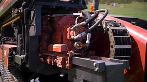 horizontal directional drilling machine hydraulic motor visible, showing hoses, mechanical parts in operation The red steel emphasizes the power behind underground boring and pipe installation
