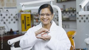 Happy smiling dentist holding dentures in hands by looking camera at hospital - concept of professional occupation, treatment and Oral care
