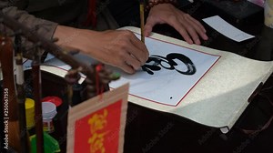 Scholar writing Vietnamese calligraphy characters on street. Scene of the calligrapher draw handwriting in penmanship at fair in springtime, this is special culture of Vietnamese when Tet come