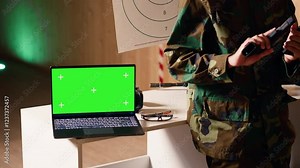 Green screen notebook next to army soldiers practicing with firearms in shooting range and having conversation. Chroma key laptop next to military units holding pistols talking, camera B