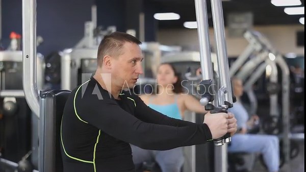 Portrait of concentrated adult man doing strength training in gym, performing chest muscles exercises on pec deck machine . High quality 4k footage