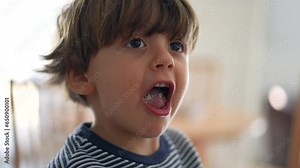 Child chewing food with open wide mouth, close-up face of little boy eating chewy food, mastication concept in deep concentration
