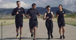 Multiethnic group of athletes running together on a panoramic countryside road. Diverse Team of joggers on morning training.