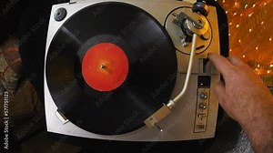 Retro player with vinyl plates twists the plate on top. The middle plan.