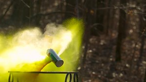 Yellow spray paint can being shot in slow motion by which it explodes and splatters aerosol paint everywhere under high pressure and begins to fly around because of it | Premium Stock Video Footage