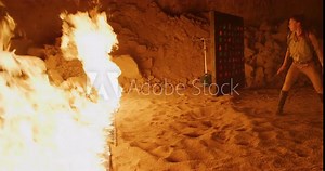Female adventurer in cave being stopped by wall of fire - slow motion