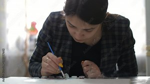 Thoughtful female artist with a patriotic makeup making a picture on a paper sheet