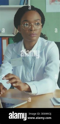 physician reviews radiograph and explains results at clinic desk, hands film to patient and gestures toward laptop Stock Video Footage - Alamy