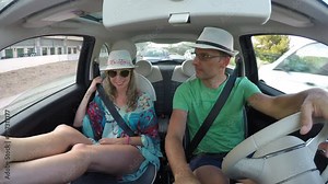 Couple in the car he is driving she with her legs on the dashboard Stock Video