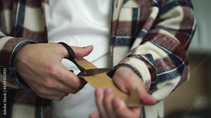 Cardboard and scissors close-up. A man cuts brown paper with scissors. Sharp scissors cutting paper