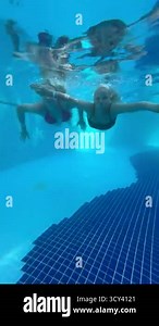 Two girls swim underwater in a pool, smiling and enjoying the moment, surrounded by bubbles and the clear blue water of a sunny day Stock Video Footage - Alamy