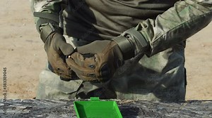 Loading a gun magazine with bullets. a close up shot of hands loading a magazine clip with bullets.