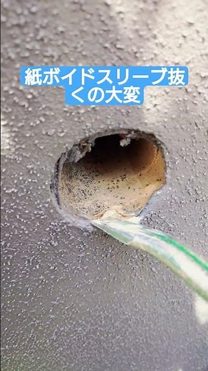 紙のボイド管をバールのようなもので抜く作業 エアコン工事