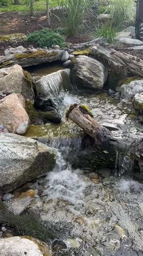 Turn your patio into a peaceful retreat ✨ This custom pondless waterfall and stream bring nature right to your backyard. #BackyardOasis #WaterFeature | Garden State Koi Pond & Waterfall Design Center