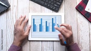 man's hand working on digital tablet at office desk, using self created chart
