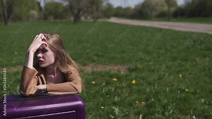 Sad traveler missed her flight and bus - Sitting on her luggage suitcase and crying - Emotions of a white caucasian female woman with light long hair wearng bra and beige jacket