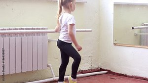 The young girl dances in a ballet tutu in the hall