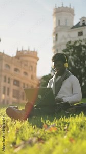 African american student using laptop in college campus while listening to music. College lifestyle.