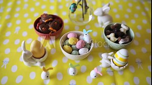 Beautiful Easter table decorated with colored eggs, rabbits, chickens, delicious sweets and chocolates served for festive breakfast on Easter.