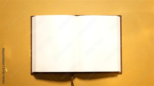 Open notebook with blank pages, brown binding, resting on a textured golden surface