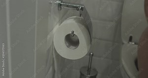 Closeup photo of woman sitting on toilet and using toilet paper