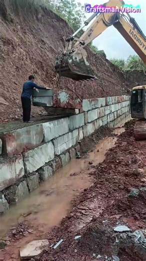Retaining Wall Construction: Excavator Lifting Square Stones for Retaining Wall Masonry