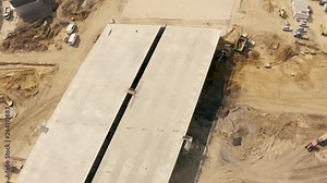 Aerial footage of a large scale highway construction site with trucks, excavators and loaders working on bridges and roads.
