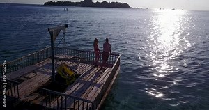 Young couple sunbathing on pontoon with drone aerial flying