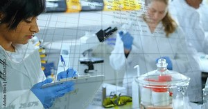 Camera shifting focus on note-taking scientist in lab recording results with floating data charts