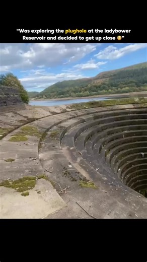 Filled Fact on Instagram: "The plughole at the Ladybower Reservoir, known as the “bellmouth spilway”, is a giant circular overflow system that automatically drains excess water when the reservoir reaches it’s maximum level, creating the dramatic illusion of a massive whirlpool. Built in the 1940s as part of the dam’s engineering design, it channels surplus water safely down a vertical shaft and through a tunnel, preventing flooding and keeping water levels stable without manual intervention. Whe