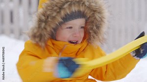 Toddler child removing snow with shovel little boy clearing path and shoveling snow in the yard. Winter kids fun outdoor.