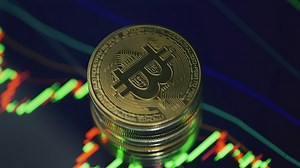 Close up of a bitcoin rotating over a digital screen - Free Stock Video